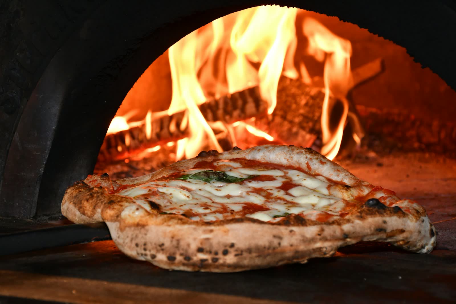 Pizza im Holzofen mit Flammen